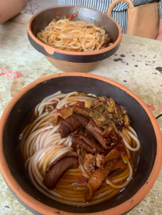 Bowl of wide, flat rice noodles with savory toppings